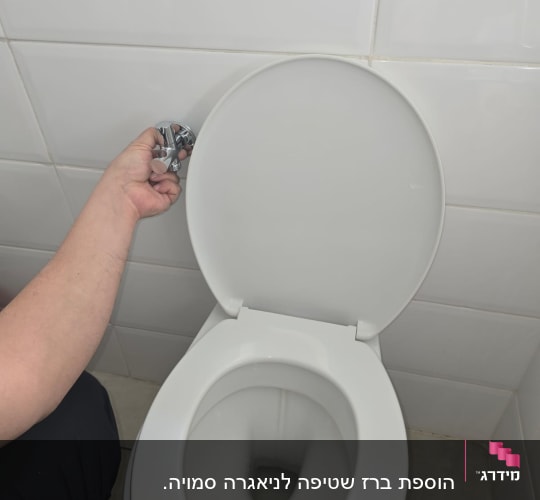 יד מחזיקה ברז ליד אסלה פתוחה